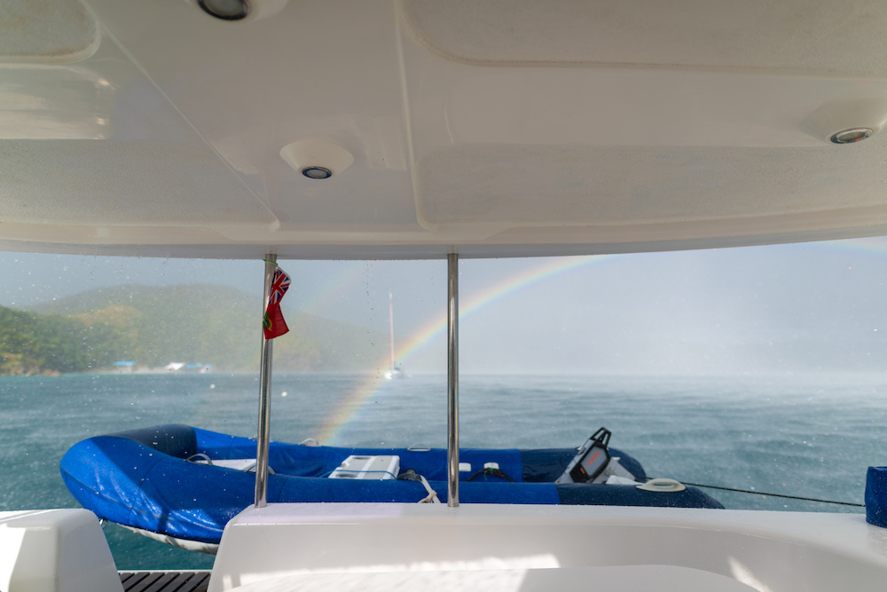 An electric dinghy on the back of the boat with a rainbow in the background